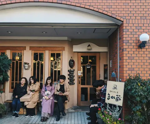 A group of friends sitting together on a bench outside a small cafe in Tokyo