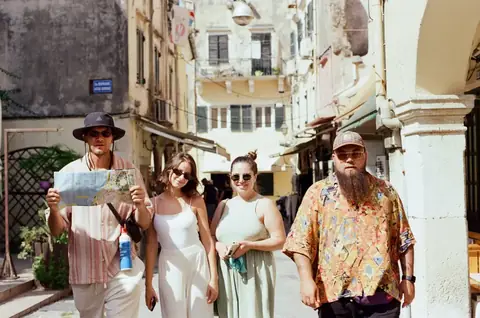 Four travelers walking together through a sunlit old city street